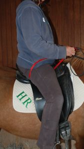 Photo 3. The rider’s back is flat with chest expanding forward/up. This connects the arms to the seat. Notice the hands are slightly higher than normal to keep an even contact on the strap while maintaining a even contact with the reins.